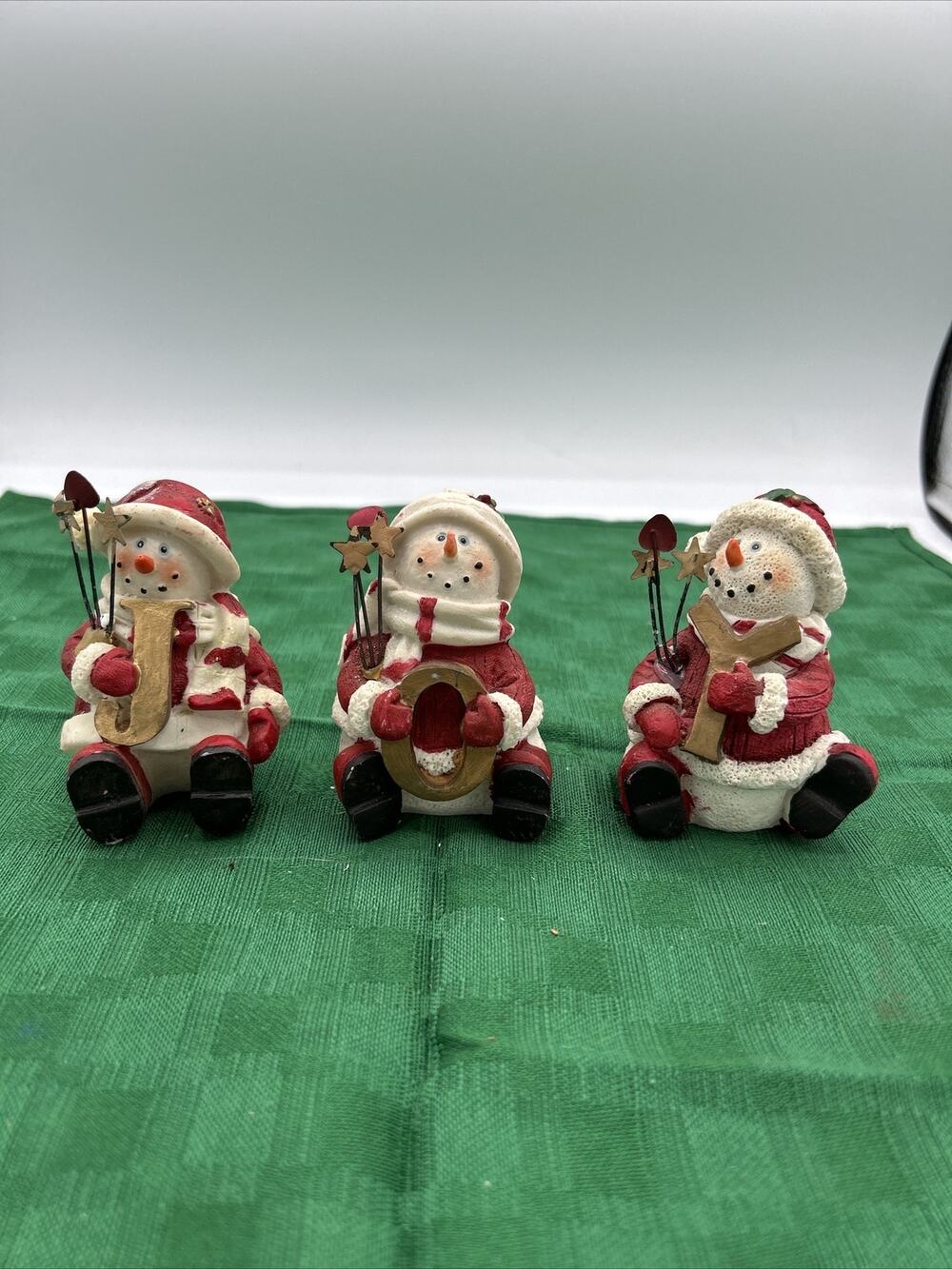 set of 3 snowman dressed like santa holding gold letters that spell JOY!